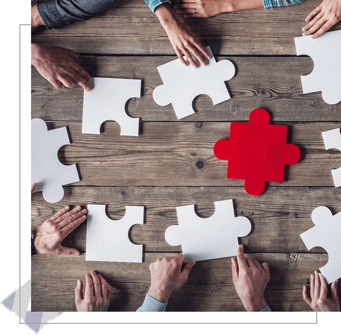 A group of people sitting at a table with puzzle pieces.